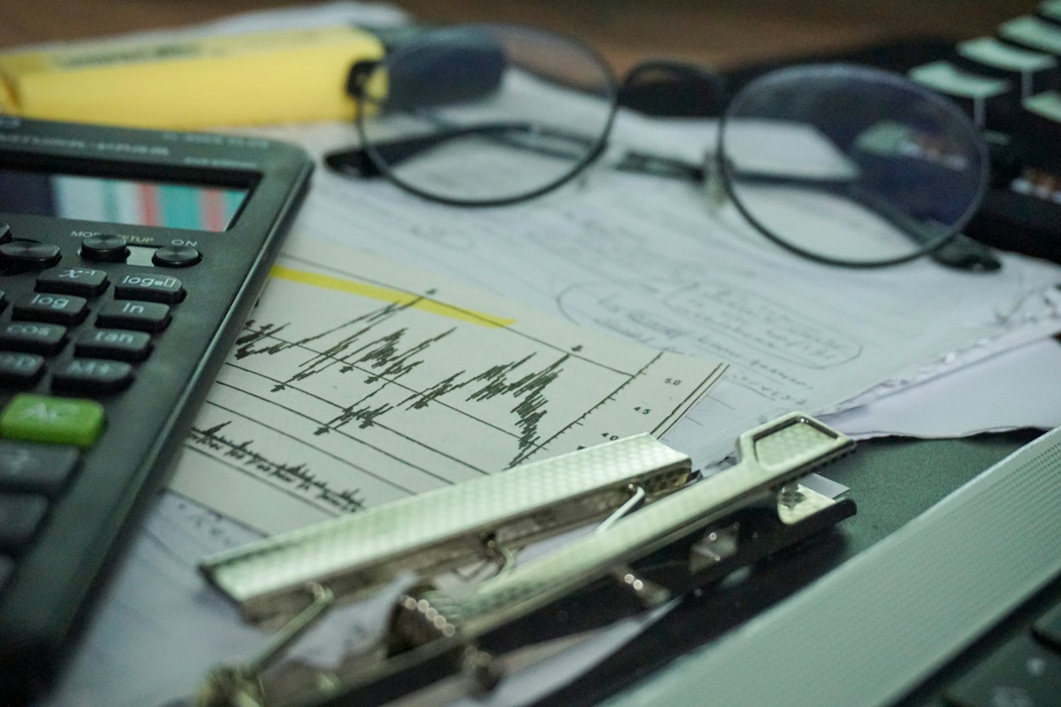 Bàn làm việc có máy tính, giấy tờ, kính và dụng cụ văn phòng